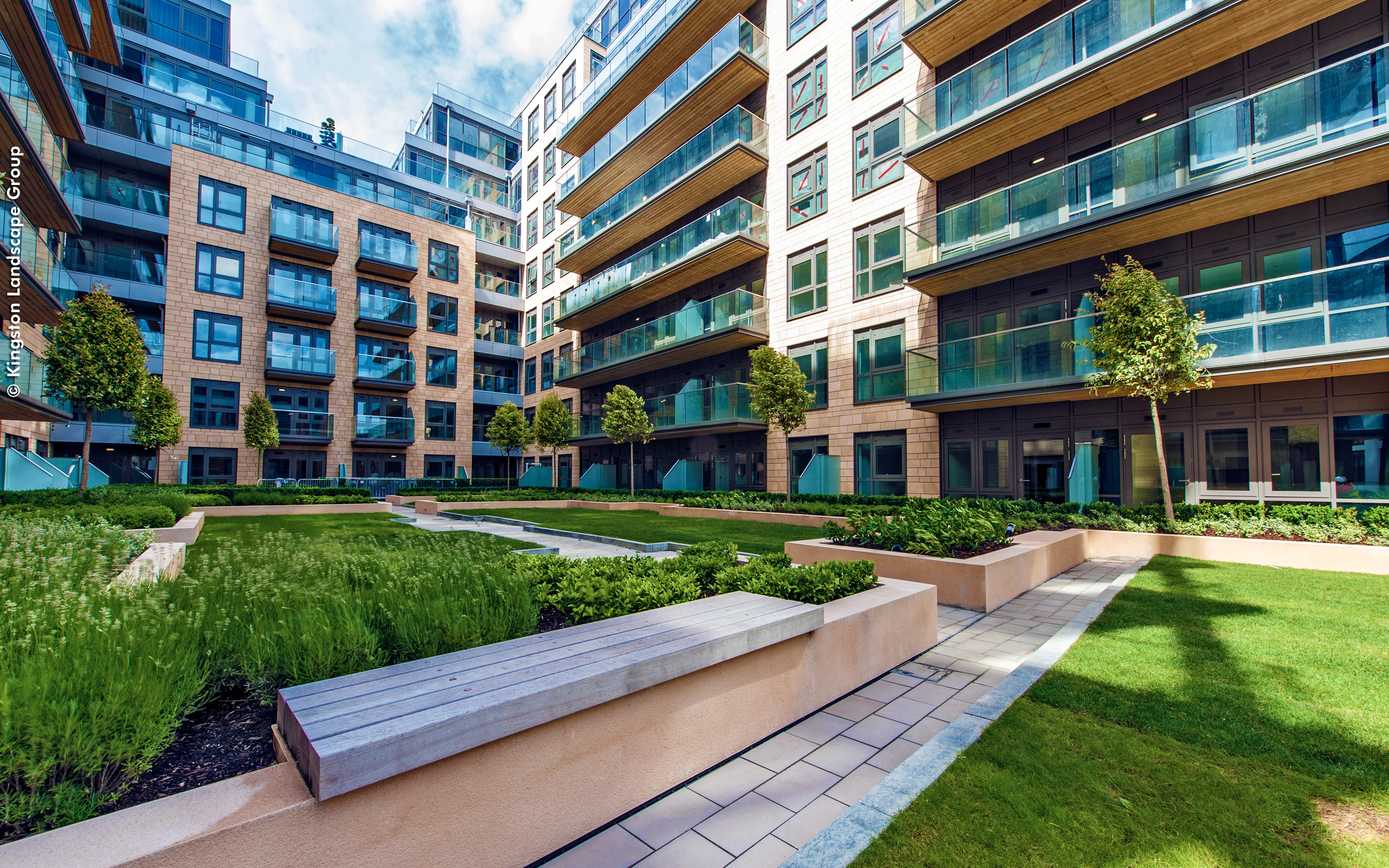 Integrated benches invite the residents to linger. Courtyard with benches, lawn and small trees surrounded by residential blocks